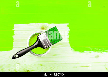 Brosse avec poignée noire sur ouvert peut d'ufo peinture verte sur la moitié du conseil en bois peint. Concept de rénovation. Banque D'Images