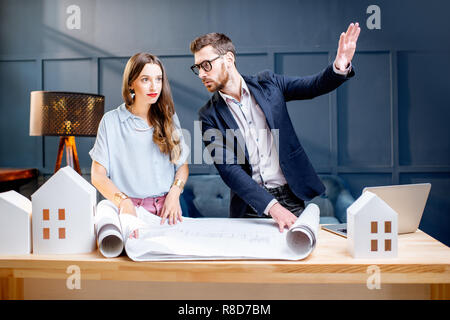 Jeune femme et l'homme en tant qu'architectes travaillant avec les bleus, ordinateur portable et de la chambre, dans l'entreprise Banque D'Images