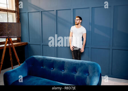 Portrait d'un homme en t-shirt blanc debout sur le mur bleu dans le luxe maison ou bureau intreior Banque D'Images