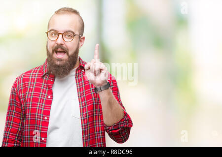 Hipster Young caucasian man wearing glasses sur fond isolé montre de l'index jusqu'à une bonne idée. Quitté et heureux. Numéro un. Banque D'Images