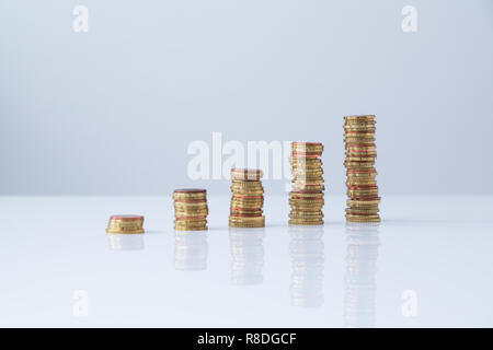 Des piles de pièces d'euros dans l'ordre croissant sur la table et l'arrière-plan gris clair. Conception simple, selective focus, Concept photo de la croissance financière. Banque D'Images