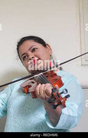 Une belle jeune femme jouant de l'instrument de musique en bois du violon. Banque D'Images