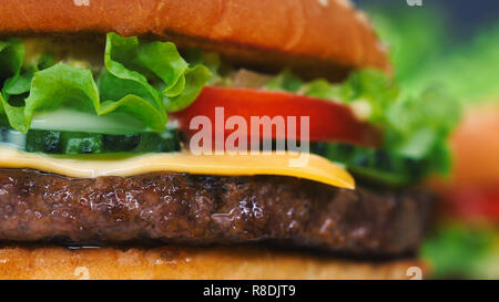 Vue détaillée de macro burger de boeuf juteux couches. Escalope, l'oignon, de légumes, de fromage fondu, de laitue, de sauce et garni de graines de sésame. Hamburger tourne. Banque D'Images