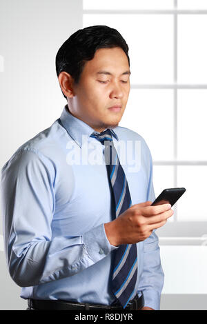 Photo image d'un beau jeune homme asiatique réussie attrayant à sérieusement les infos dans son son smart phone Banque D'Images
