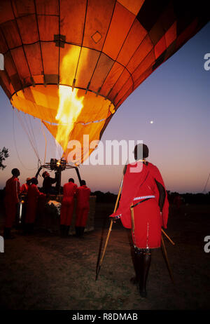 En regardant un guerrier Masai hot air baloons prépare à décoller tôt le matin, Masai Mara, Kenya Banque D'Images