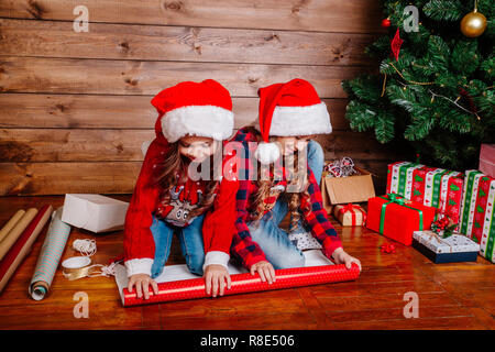 Happy funny Little Sisters dans Santa hats cadeaux pack near Christmas Tree Banque D'Images