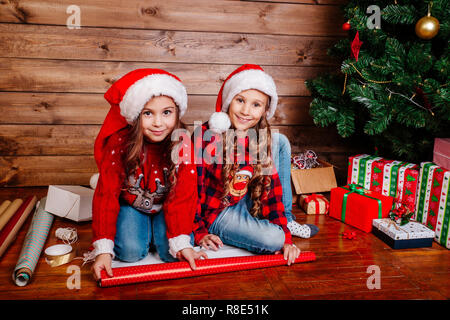 Happy funny Little Sisters dans Santa hats cadeaux pack near Christmas Tree Banque D'Images