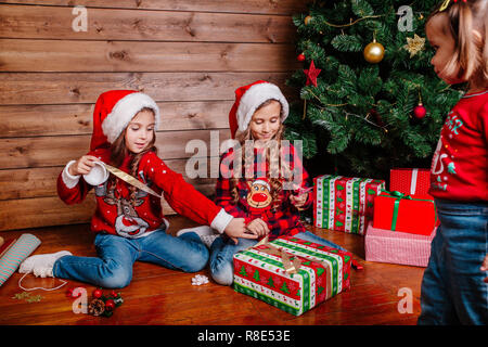 Happy funny Little Sisters dans Santa hats cadeaux pack near Christmas Tree Banque D'Images