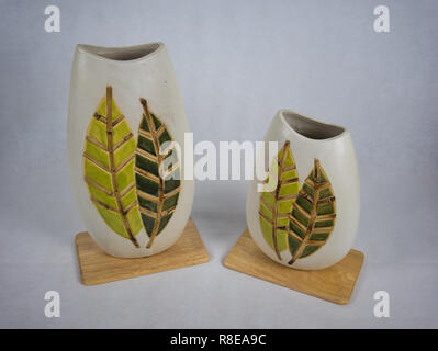 Deux vases de différentes tailles en terre cuite avec motif de feuille sur une planche en bois Banque D'Images