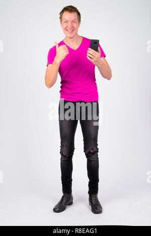 Full body shot of young man using phone et giving Thumbs up Banque D'Images