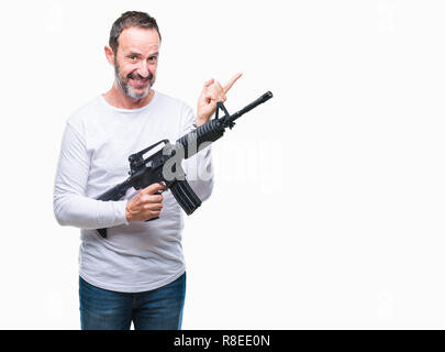 L'âge moyen des cadres supérieurs de l'homme criminel holding gun arme sur fond isolé très heureux pointant avec la main et le doigt sur le côté Banque D'Images