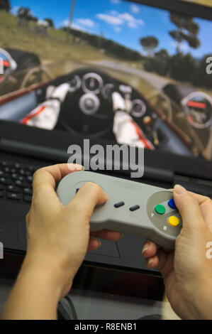 Close-up d'une personne jouant avec la manette de jeu sur l'ordinateur en regardant un jeu vidéo sur l'écran Banque D'Images