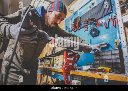 Un homme en vêtements de travail un réparateur à un atelier ski service ski une surface de glissement, polissage, Base de ski finale le polissage. Dans les mains d'une brosse électrique Banque D'Images