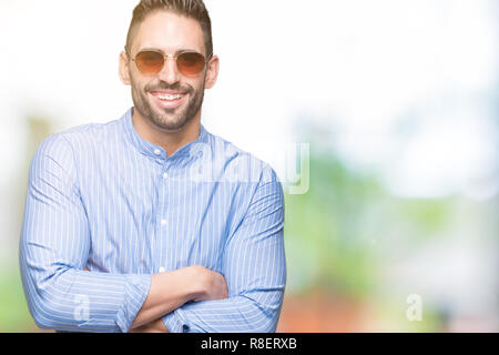 Les jeunes bel homme portant des lunettes de soleil sur fond isolé heureux face smiling avec bras croisés regardant la caméra. Personne positive. Banque D'Images