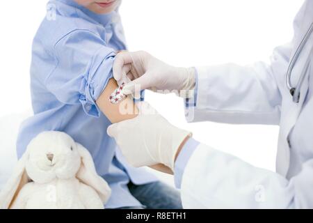 Médecin mettre le plâtre sur le bras du garçon après l'injection. Banque D'Images
