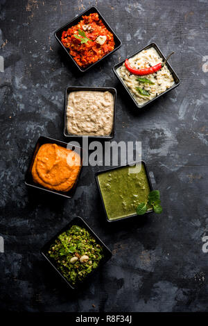 Groupe des chutneys indiens comprend des noix de coco, d'arachide, vert et rouge, l'ail frais et pudina servies dans de petits bols de forme carrée au point sélective. Banque D'Images