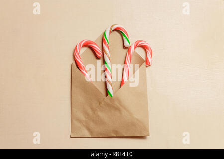 Vue de dessus trois cannes de bonbon en enveloppe brune sur fond de bois de couleur brune. Banque D'Images