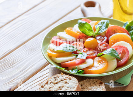 Close-up plaque verte d'une cuisine italienne cuisine salade caprese sur board sur table en bois. Banque D'Images