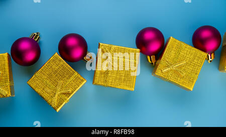 Boules mauve fête cadeaux d'or sur fond bleu. Composition de Noël. Banque D'Images