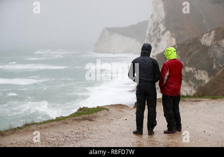 Les gens vous regarde la mer difficile près de Durdle Door dans le Dorset comme amber alerte mises en garde de l'accumulation de neige et de glace ont été émis pour le nord de l'Angleterre et des Midlands. Banque D'Images