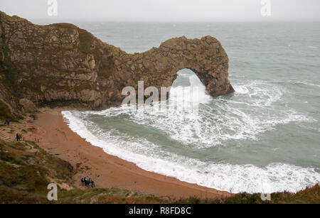 Les gens sur la plage regarder les vagues déferlent sur Durdle Door dans le Dorset comme amber alerte mises en garde de l'accumulation de neige et de glace ont été émis pour le nord de l'Angleterre et des Midlands. Banque D'Images