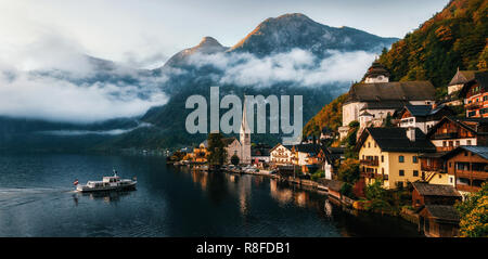 Bouilloire petit ferry arrive au quai de la ville de Hallstatt se reflétant dans le lac Hallstattersee dans Alpes autrichiennes en matin, région du Salzkammergut, Autriche Banque D'Images