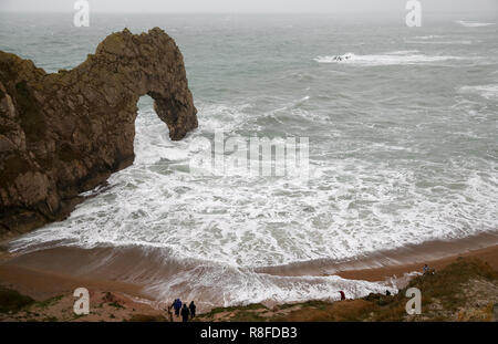 Les gens sur la plage regarder les vagues déferlent sur Durdle Door dans le Dorset comme amber alerte mises en garde de l'accumulation de neige et de glace ont été émis pour le nord de l'Angleterre et des Midlands. Banque D'Images