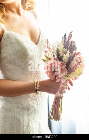 Bride holding a bouquet de rose, violet et jaune fleurs avec une perle bracelet piscine Banque D'Images