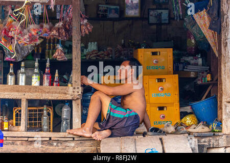 Thakhek, Laos - 20 Avril 2018 : homme assis dans son petit supermarché dans une région rurale isolée du Laos Banque D'Images