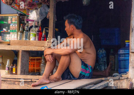 Thakhek, Laos - 20 Avril 2018 : homme assis dans son petit supermarché dans une région rurale isolée du Laos Banque D'Images