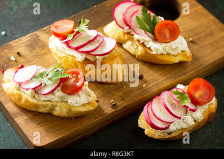 En-cas d'Antipasti définie pour le vin. Brushetta ou Crostini avec baguette grillées, fromage, radis et tomates servi sur une planche en bois rustique sur une pierre ta Banque D'Images