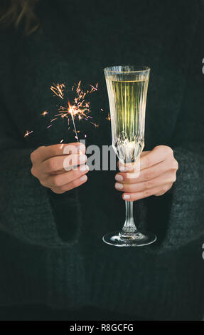 Noël ou Nouvel An fête concept. Femme pull en laine gris foncé en tenant le verre de champagne et de fête traditionnel cierges en mains, cl Banque D'Images
