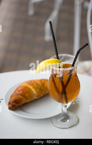 Verre avec du grog et un croissant Banque D'Images