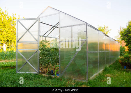 Serre en polycarbonate dans le jardin. Toit triangulaire. Banque D'Images