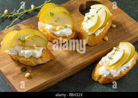 Antipasti des collations pour le vin. Brushetta avec fromage et poire servi sur une planche en bois rustique sur une table en pierre. Banque D'Images
