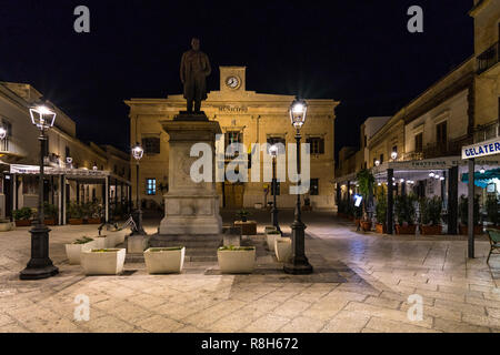 Vue de la nuit de l'hôtel de ville de Favignana et la statue d'Ignazio Florio, Favignana, Sicile, Italie Banque D'Images