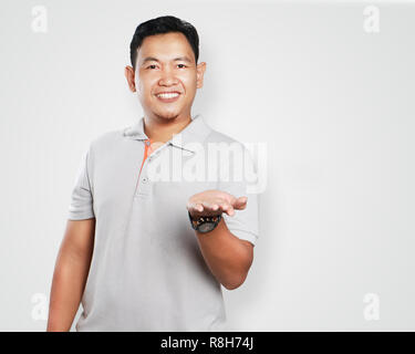 Photo image portrait of a cute handsome Young Asian man smiling et montrant sa main gauche paume ouverte Banque D'Images