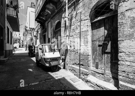 Image en noir et blanc de Sciacca vieille ville avec un Piaggio Ape véhicule trois-roues près de bâtiments anciens. Sciacca, Sicile, Italie, mai 2018 Banque D'Images