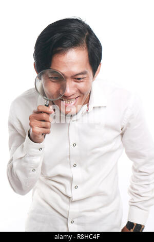 Photo image portrait d'un drôle de jeune homme d'Asie de l'air très heureux et souriant pour trouver quelque chose tout en regardant dans loupe, Close up Banque D'Images