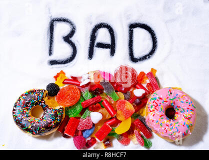 Sélection de bonbons bonbons colorés et le traite avec mauvais mot écrit sur le sucre blanc en sucre dans l'alimentation des enfants cause des problèmes de santé Nutrition Obesit Banque D'Images