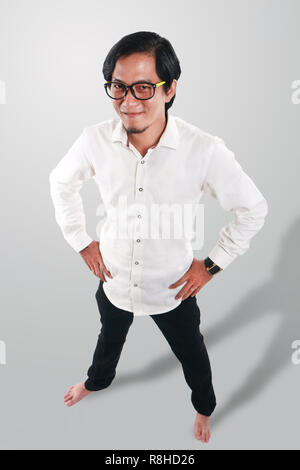 Photo image portrait d'un drôle de Young Asian man wearing glasses semblait très fier et heureux, souriant avec les deux mains sur sa taille, un corps entier portrait Banque D'Images