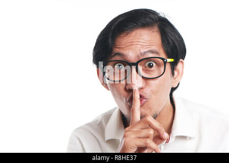 Photo image portrait d'un drôle de jeune businessman wearing glasses montrant signe ssh, portrait d'un doigt sur les lèvres lui demandant de garder le silence Banque D'Images