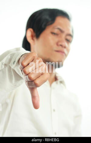 Photo image portrait d'un drôle de Young Asian man showing thumb down geste avec déçu face, vue latérale moitié du corps, portrait sur fond blanc, f Banque D'Images