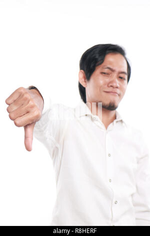 Photo image portrait of a cute funny Young Asian man showing thumb down geste avec moquerie face, portrait sur fond blanc Banque D'Images