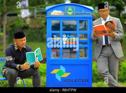 Gouverneur de Java Ouest Ridwan Kamil (à droite) avec le maire de Bogor Bima Arya (gauche) lire un livre lors du lancement de la Smart Case d'alphabétisation (Kolecer) service en Sempur Park. Kolecer, qui a été lancé par le Bureau régional Archives Bibliothèque (Dispusipda) de la province de Java ouest, sous la forme d'une mini-bibliothèque dans un espace public capable de charger 80 livres comme une forme d'innovation pour que les gens puissent occuper leur temps par la lecture. Banque D'Images