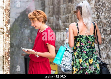 La Croatie, Split - Septembre 22th, 2018 : A young woman standing en utilisant une calculatrice à l'extérieur du contrôle du prix de ses vêtements store, Split, Croatie. Banque D'Images