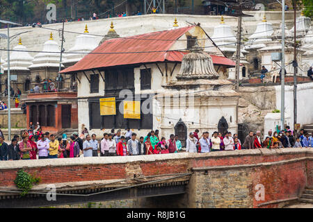 Les gens sur un pont à regarder un funérailles hindoues sur le ghat sur la rivière Bagmati au temple de Pashupatinath sacré hindou à Katmandou, Népal Banque D'Images