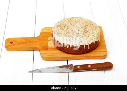 Gâteau aux carottes sucrées faites maison avec les noix, la cannelle et le glaçage blanc sur la table en bois blanc Banque D'Images