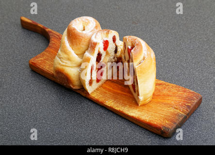 Pains faits maison sweet swirly avec raisins secs, canneberges et cerises saupoudrée de sucre en poudre sur le tableau noir. L'accent peu profondes. Banque D'Images