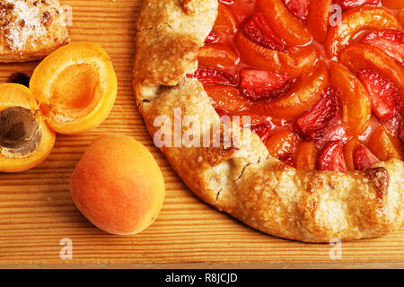 Tarte maison Gros plan galette avec les pêches et les fraises et les pêches jaunes fraîches sur la table en bois. Vue d'en haut. Banque D'Images